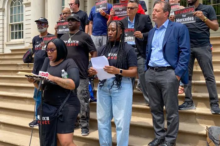 Mercedes Pope, front, calls for police accountability at a press conference outside City Hall Monday. She says she was pepper sprayed when she tried to record officers in April 2020.